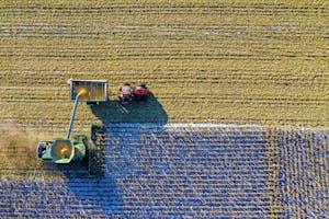 Home 9 Drone captures vibrant aerial view of tractors harvesting corn in Minnesota field.